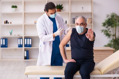Yaşlı adam covid-19 aşı konseptinde genç doktoru ziyaret ediyor.