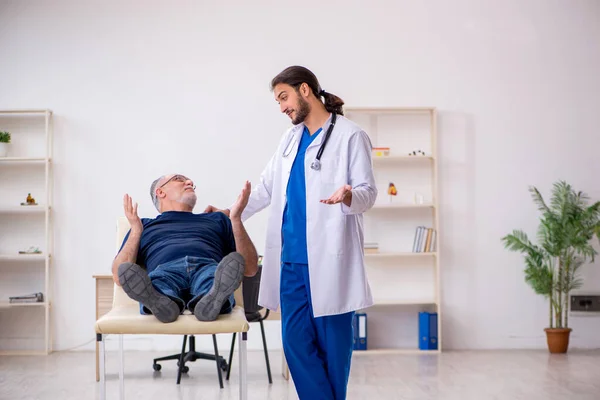 Oude mannelijke patiënt op bezoek bij jonge mannelijke arts chiropractor — Stockfoto