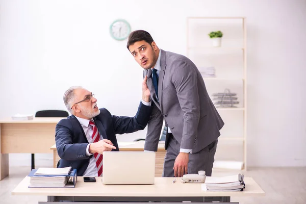 Viejo jefe y joven empleado masculino que trabaja en la oficina —  Fotos de Stock