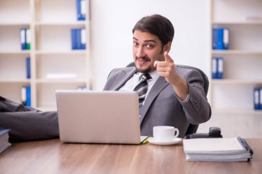 Genç çekici erkek çalışan işyerinde oturuyor.