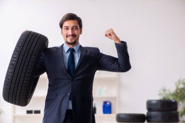 Genç adam ofiste lastik satıyor.