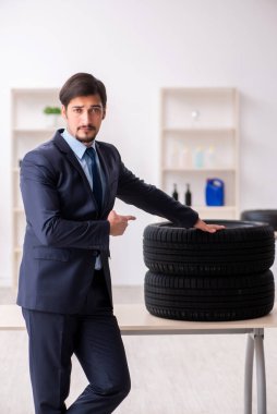 Genç adam ofiste lastik satıyor.