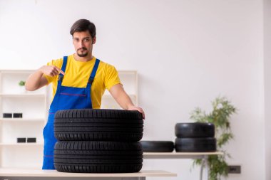 Atölyede lastiği olan genç bir erkek tamirci.