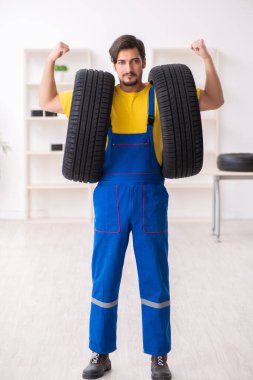 Atölyede lastiği olan genç bir erkek tamirci.