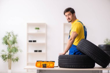 Atölyede lastiği olan genç bir erkek tamirci.