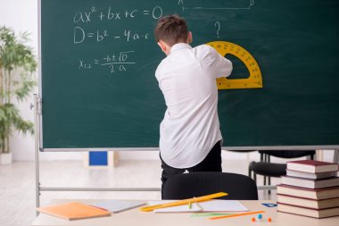 Okul çocuğu tahtanın önünde geometri okuyor.