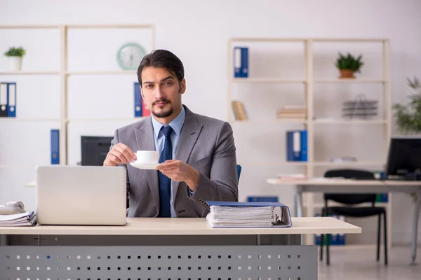 Junge männliche Angestellte trinkt in der Pause Kaffee — Stockfoto