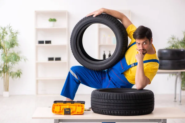 Mladý pracovník garáže s pneumatikou v dílně — Stock fotografie