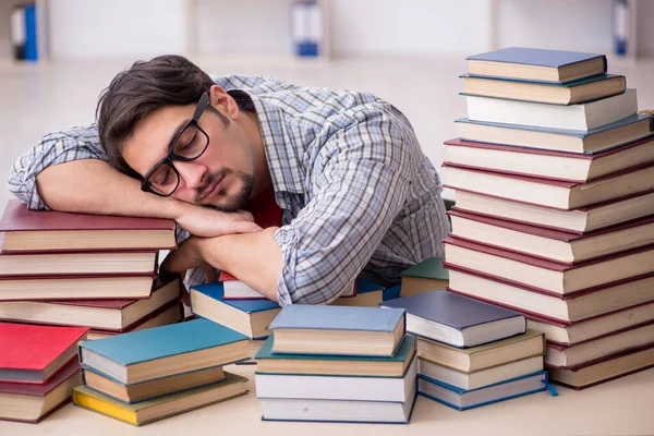 Jovem estudante do sexo masculino e muitos livros em sala de aula — Fotografia de Stock