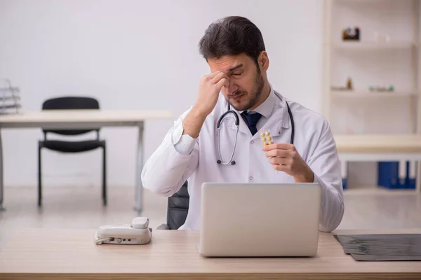 Young male doctor holding pills in the clinic — Stock Photo, Image