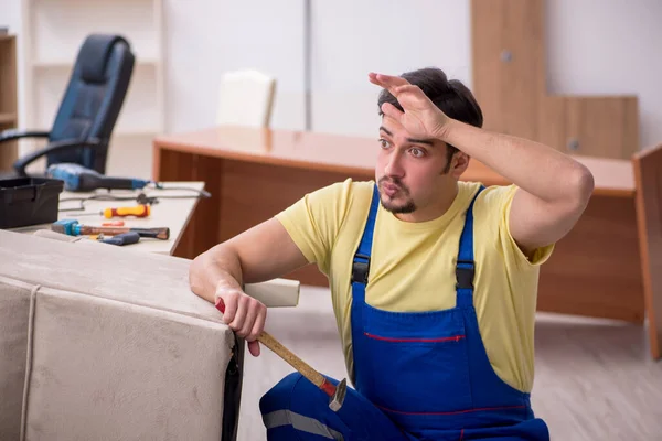 Jonge mannelijke timmerman repareert fauteuil op kantoor — Stockfoto