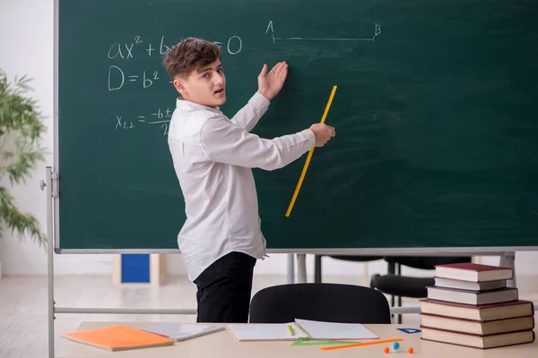 Schoolboy studying geometry in front of blackboard — Stock Photo, Image