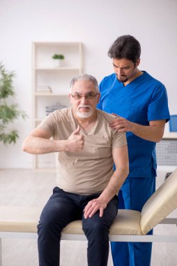 Yaşlı erkek hasta genç erkek doktor kayropraktik uzmanı.