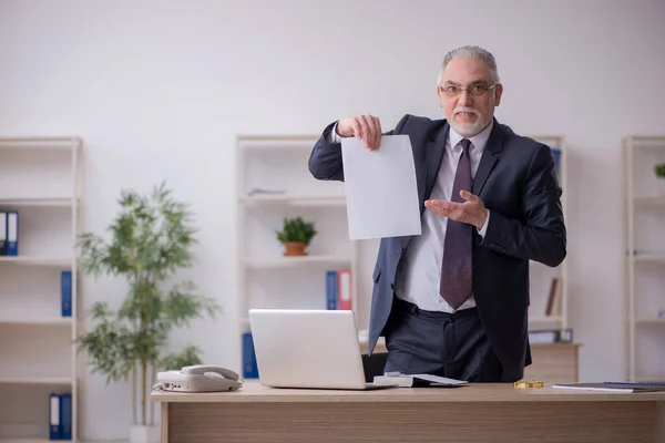 Starý muž zaměstnanec sedí na pracovišti — Stock fotografie