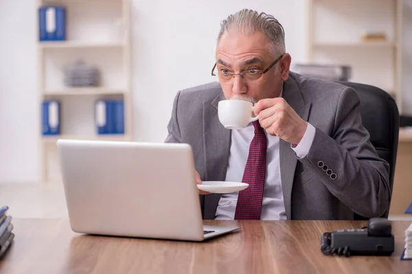 Vieil employé masculin buvant du thé pendant la pause — Photo