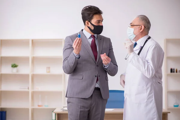 젊은 사업가가 예방 접종을 위해 연로 한 남성 의사를 방문하다 — 스톡 사진