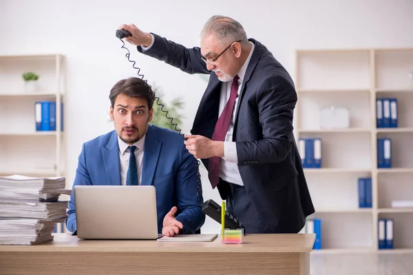 Velho chefe e jovem empregado masculino no conceito de bullying — Fotografia de Stock