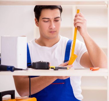 İşçi adam montaj kitaplığını tamir ediyor