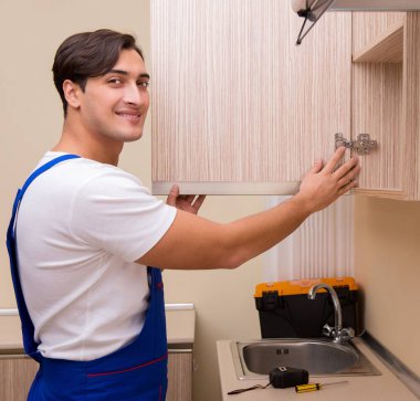 Genç adam mutfak mobilyalarını monte ediyor.