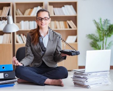 İş kadını ofiste meditasyon yapıyor.