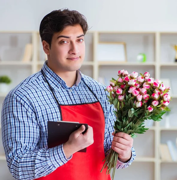 Çiçekçi asistanı bir demet çiçek veriyor.