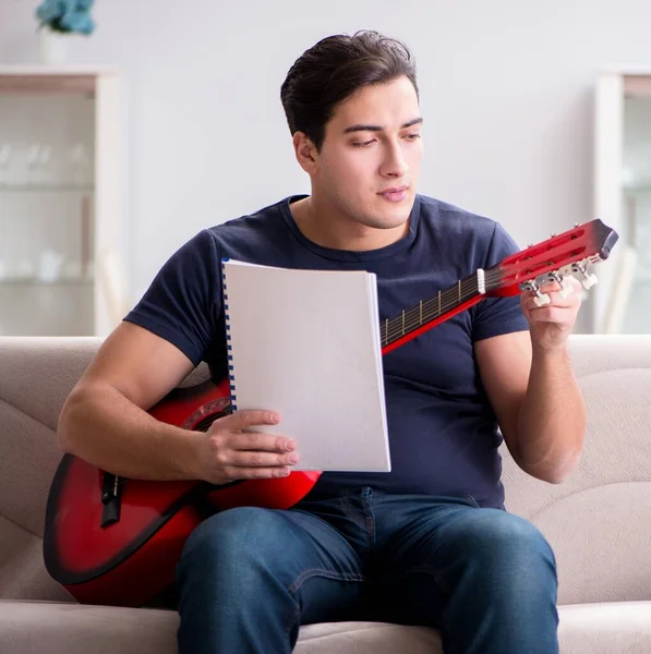 Mladý muž cvičí doma na kytaru — Stock fotografie