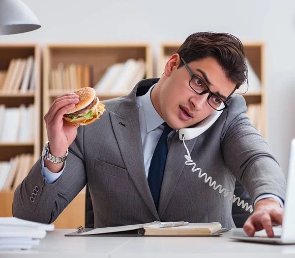 Hambriento empresario divertido comer sándwich de comida chatarra — Foto de Stock