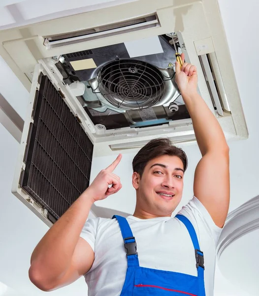 Worker repairing ceiling air conditioning unit