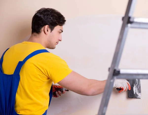 Empregado jovem empreiteiro aplicando gesso na parede — Fotografia de Stock