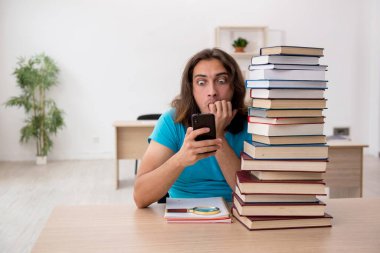 Genç bir erkek öğrenci ve sınıfta bir sürü kitap var.