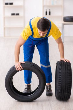 Atölyede lastiği olan genç bir erkek tamirci.