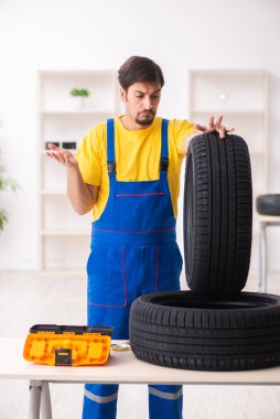 Atölyede lastiği olan genç bir erkek tamirci.