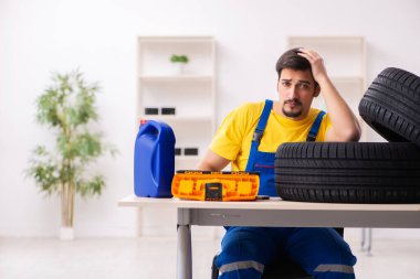 Atölyede lastiği olan genç bir erkek tamirci.