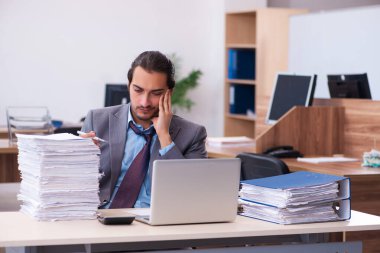 Ofisteki aşırı işten memnun olmayan genç bir erkek işçi.