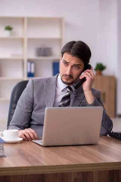 Jeune homme attrayant assis sur le lieu de travail — Photo