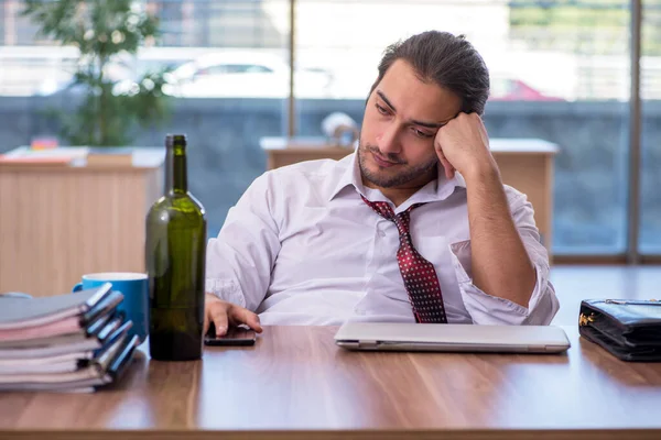 Jonge mannelijke alcoholverslaafde werknemer die op kantoor werkt — Stockfoto