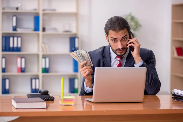Mladý zaměstnanec, který drží bankovky v kanceláři — Stock fotografie