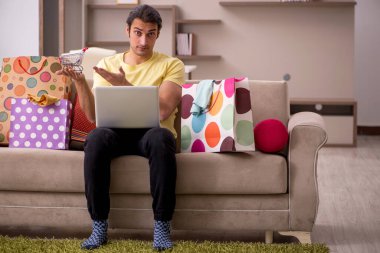 Evde bir sürü çantası olan genç bir adam var.