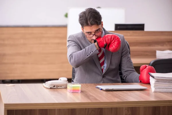 Ung man anställd bär boxningshandskar på arbetsplatsen — Stockfoto