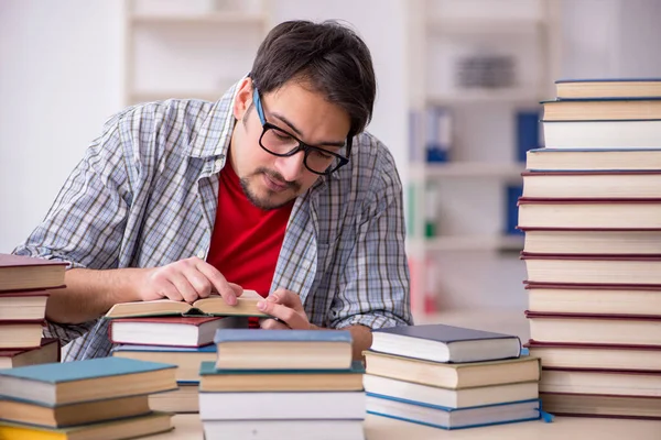 Joven estudiante masculino y demasiados libros en el aula — Foto de Stock