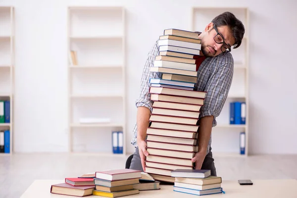 Joven estudiante masculino y demasiados libros en el aula — Foto de Stock