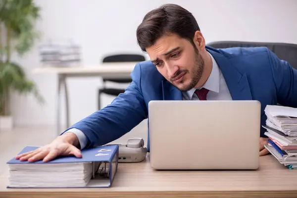 Jovem funcionário masculino e muito trabalho no escritório — Fotografia de Stock