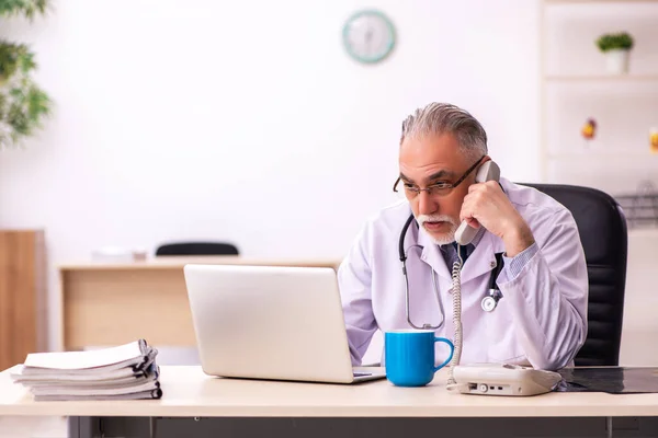 Verouderde mannelijke arts werkzaam in de kliniek — Stockfoto