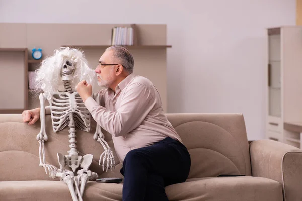 Kanepede oturan yaşlı adam ve kadın iskeleti. — Stok fotoğraf