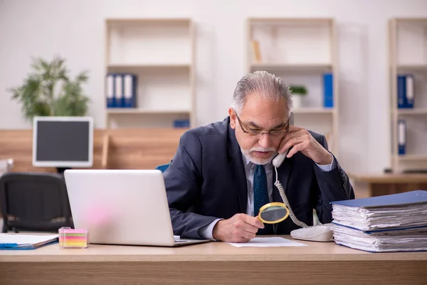 Vecchio revisore dei conti dipendente maschio tenendo loupe sul posto di lavoro — Foto Stock