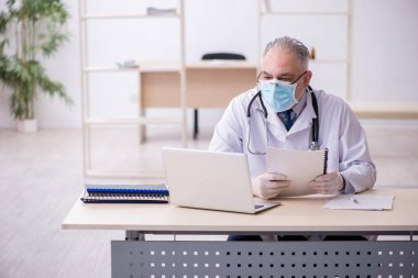 Klinikte çalışan yaşlı erkek doktor.