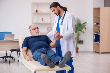 Yaşlı erkek hasta, genç erkek doktor masörünü ziyaret ediyor.