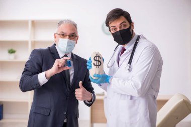 Yaşlı işadamı aşı danışmanıyla genç erkek doktoru ziyaret ediyor.