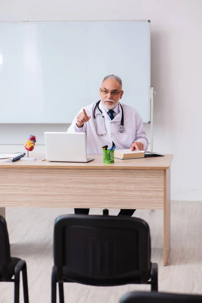 Yaşlı erkek doktor, salgın sırasında sınıfta ders veriyor. — Stok fotoğraf