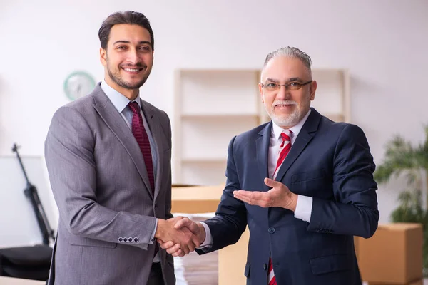 Young realtor and old boss in relocation concept — Stock Photo, Image